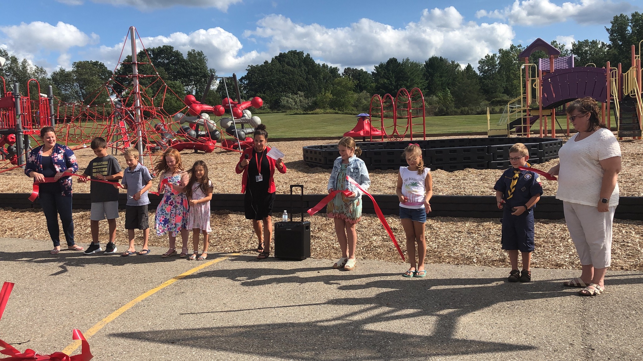 Parents and students with Mrs. Kott all cutting the ribbon at the same time.
