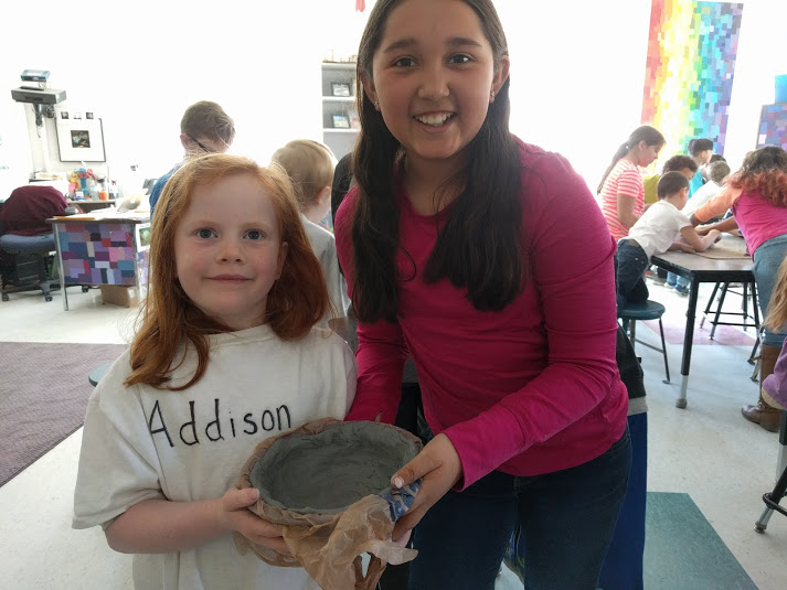 Two girls showing the bowl they made