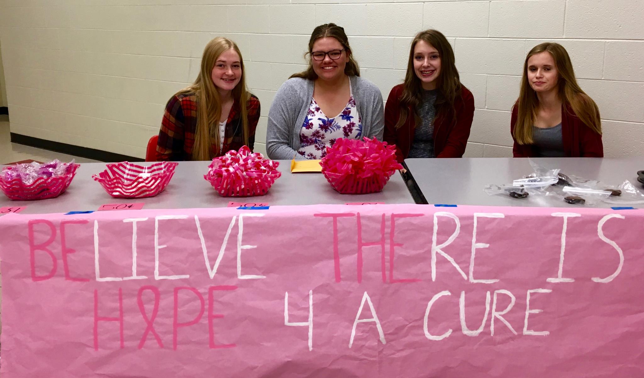 Girls at table with banner "believe there is hope for a cure"