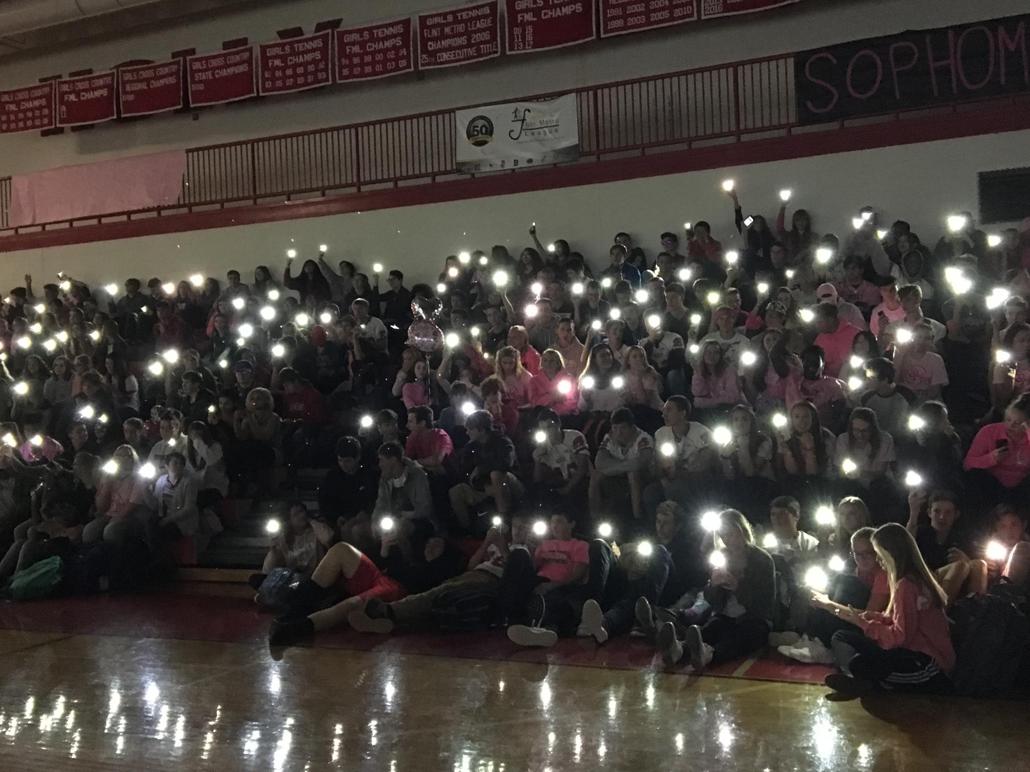 Students in the Gym with lights out and flashlights in memory of cancer patients