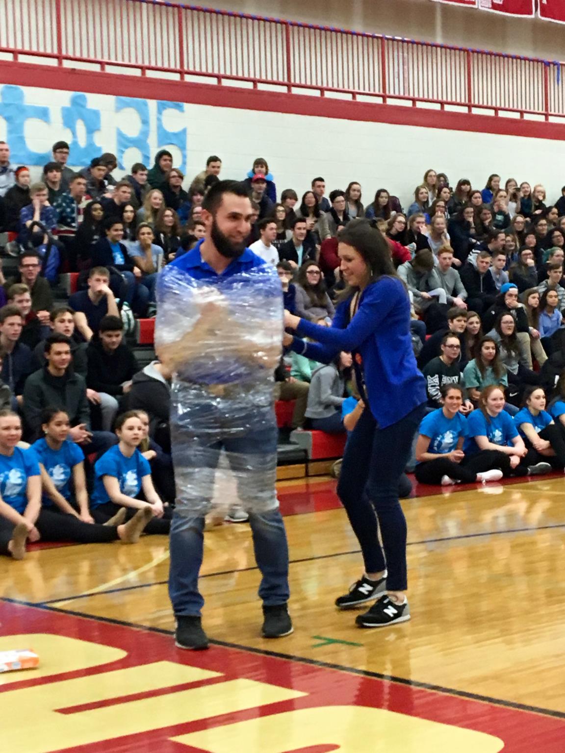 Student wrapping staff member in plastic wrap