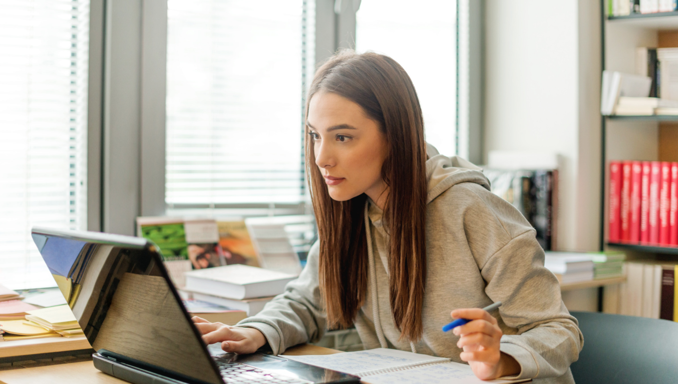 Female student working at desk using laptop