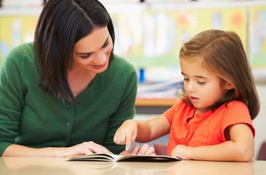 Student with teacher reading a book